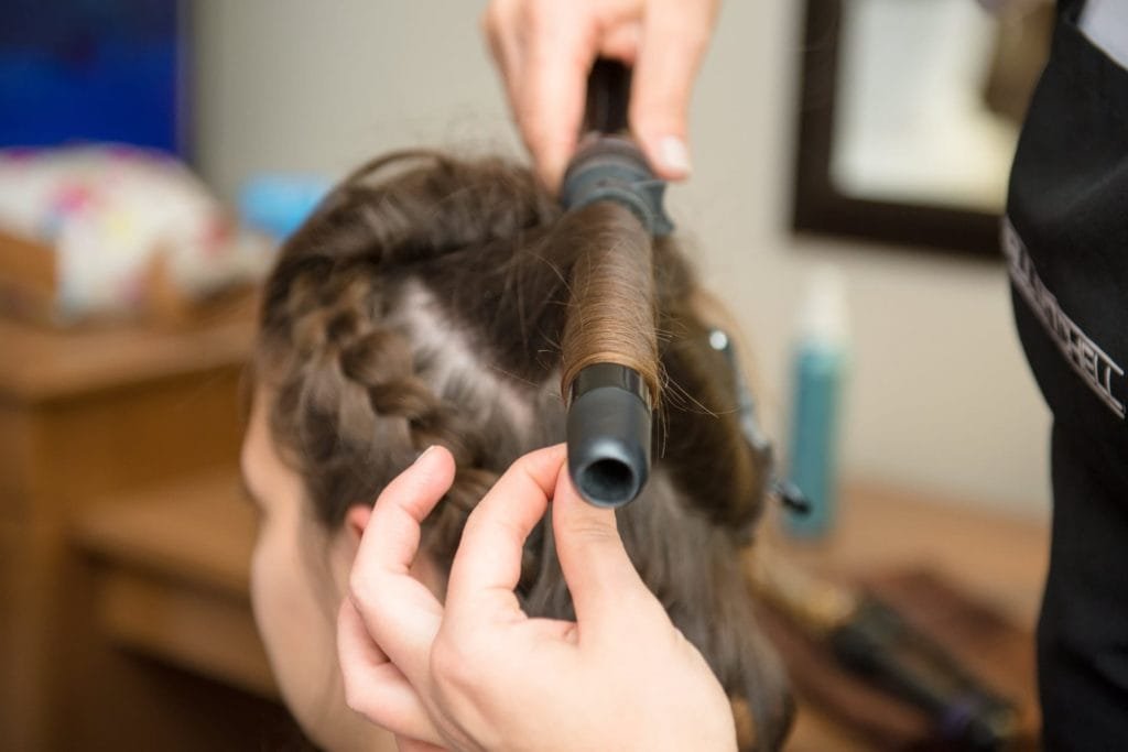 Eine Frau lässt sich von einem Lockendreher die Haare frisieren.